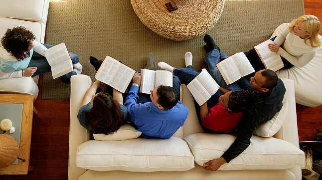 Draufsicht auf eine Gruppe von Menschen, die mit Bibeln im kreis sitzen